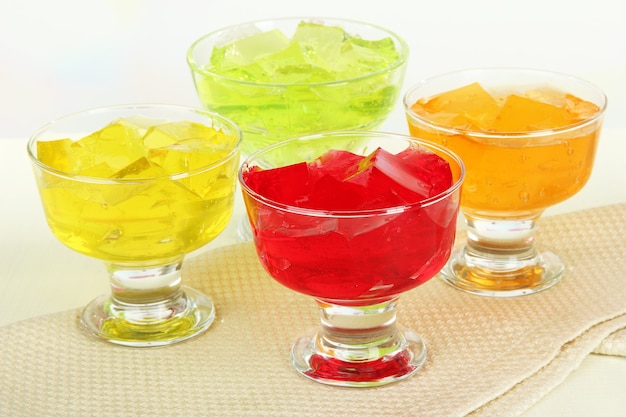 Tasty jelly cubes in bowls on table on light