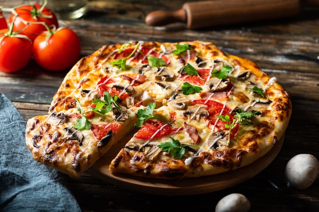 Tasty juicy pizza on wooden background. lots of meat and\
cheese. mushroom pizza. pepperoni pizza. mozzarella and tomato.\
italian dish. italian food. comfort food. local food