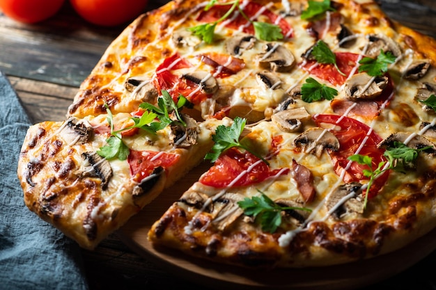 Tasty juicy pizza on wooden background. lots of meat and cheese. Mushroom pizza. Pepperoni pizza. Mozzarella and tomato. Italian dish. Italian food. Comfort food. Local food