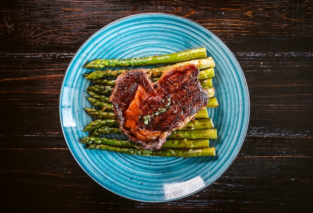 Вкусный и сочный стейк и спаржа, наполовину обжаренные на сковороде и посыпанные тертым сыром Пармезан