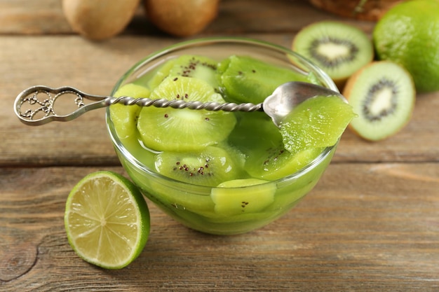 Tasty kiwi jam in glass bowl on wooden background