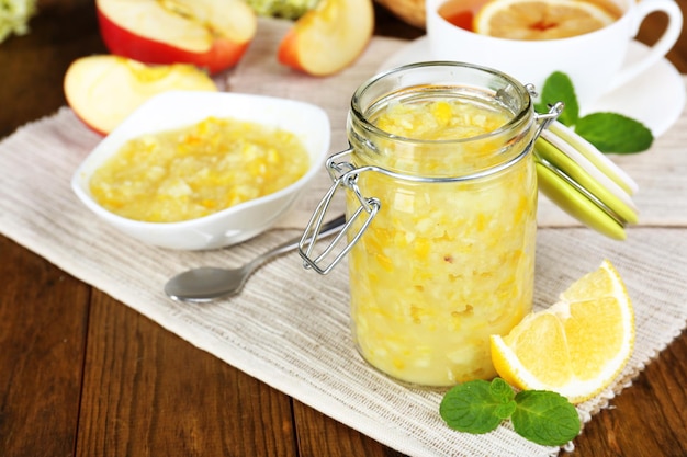 Tasty lemon jam with cup of tea on table closeup