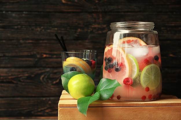 Tasty lemonade with citrus fruits and berries in glassware on wooden crate