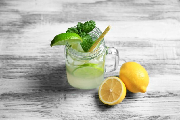 Photo tasty lemonade with lime and mint in mason jar on table