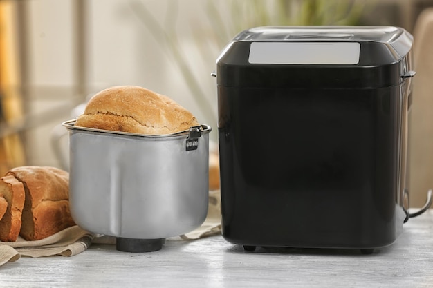 Tasty loaf and bread machine on table