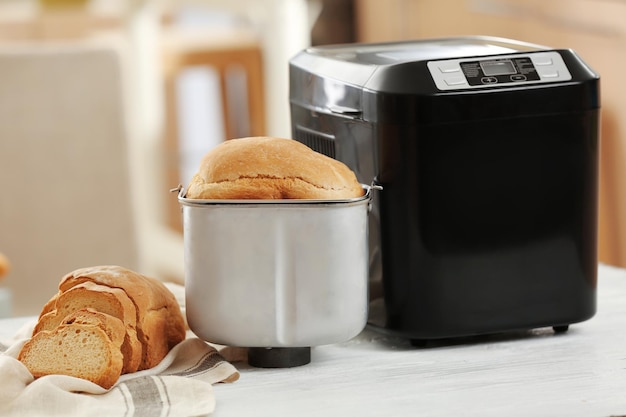 Tasty loaf and bread machine on table