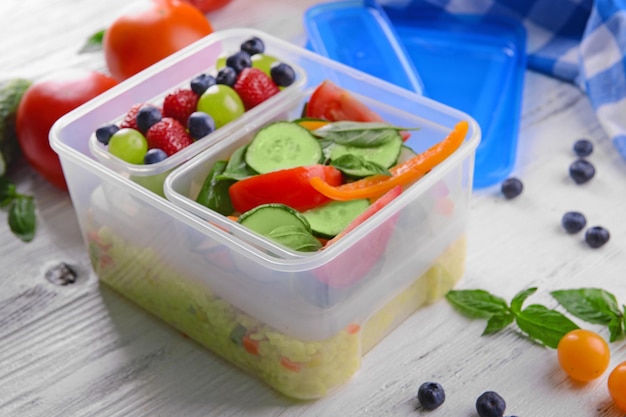 Tasty lunch in plastic containers on wooden table close up