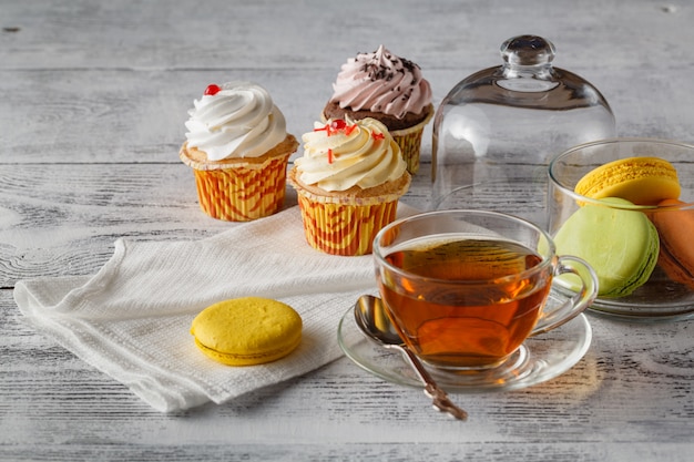 Tasty macaroons with tea on wooden table