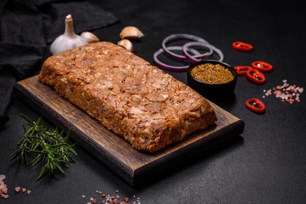 Tasty meat brawn or roll on a wooden cutting board with spices and herbs