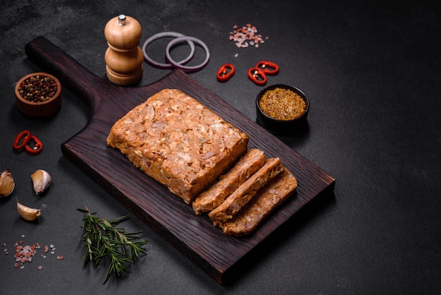 Tasty meat brawn or roll on a wooden cutting board with spices and herbs