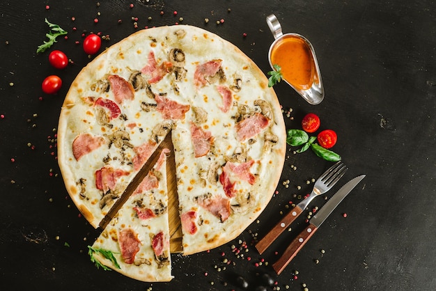 Tasty meat pizza with various ingredients on black background