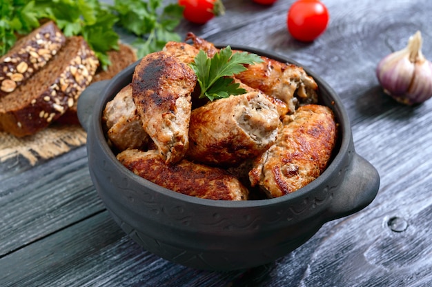 Tasty meat rolls with mushrooms in a ceramic pot on a wooden surface