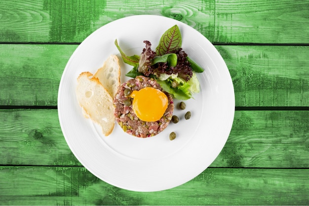 Tasty meat in white plate on wooden background