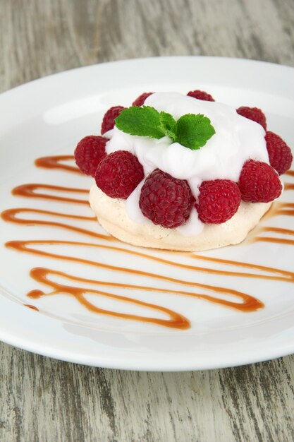 Photo tasty meringue cake with berries on wooden table