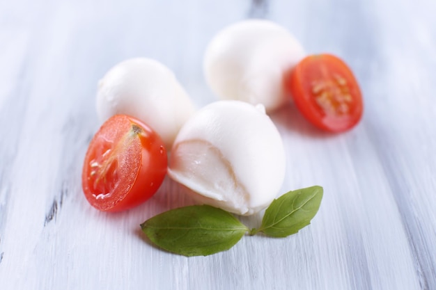 Tasty mozzarella cheese with basil and tomatoes on wooden table