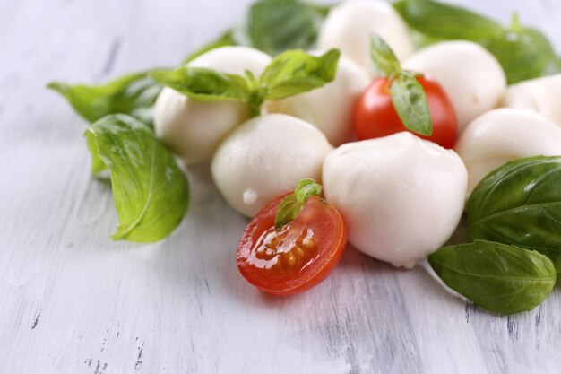 Tasty mozzarella cheese with basil and tomatoes on wooden table