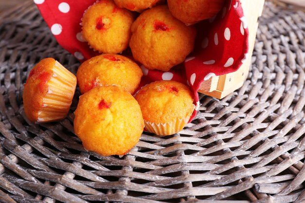 Tasty muffins with red currant on wicker mat background