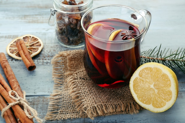 Tasty mulled wine and spices, on blue wooden background, close-up