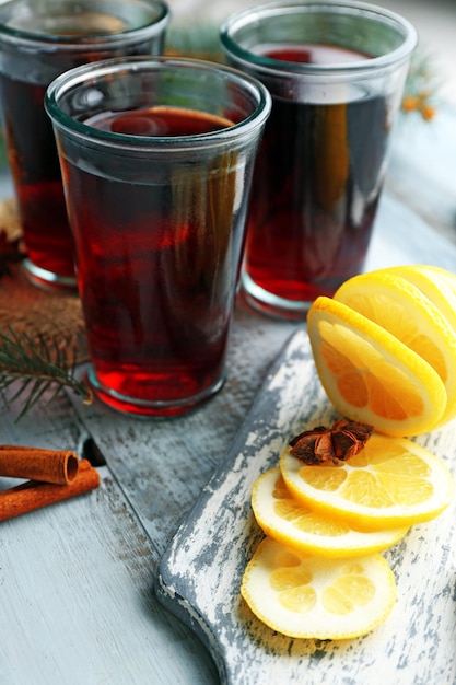 Tasty mulled wine and spices, on blue wooden background, close-up