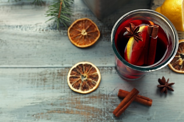 Tasty mulled wine and spices, on blue wooden surface, close-up