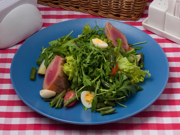 Tasty nicoise salad on a blue plate in a restaurant