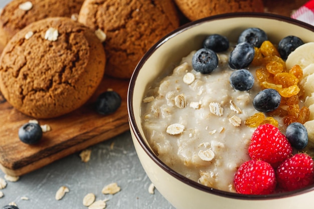 tasty nutritious oatmeal with fruits and berries on a light stone background