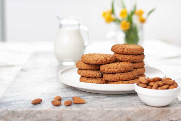 Tasty oatmeal and almond cookies with jar of milk on the old marble table