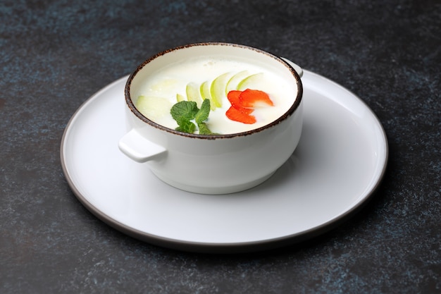 Tasty oatmeal with apple, strawberry and mint in bowl on table