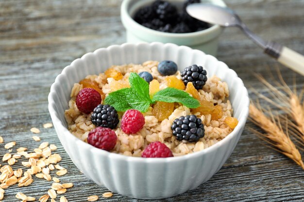 Tasty oatmeal with berries in bowl on table