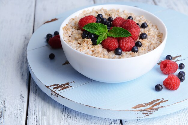 Tasty oatmeal with berries on table close-up