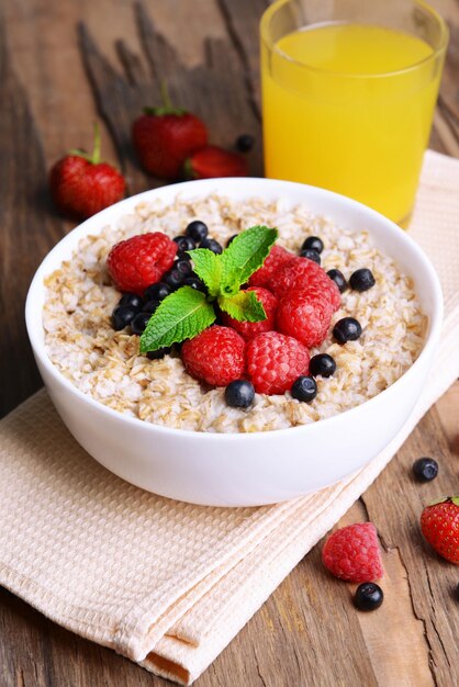 Tasty oatmeal with berries on table closeup