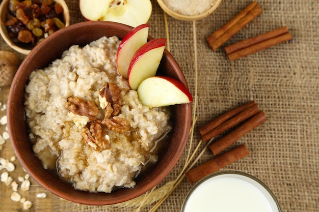 tasty oatmeal with nuts and apples on table close up