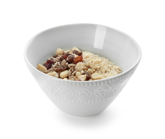 Tasty oatmeal with nuts and raisins in bowl on white