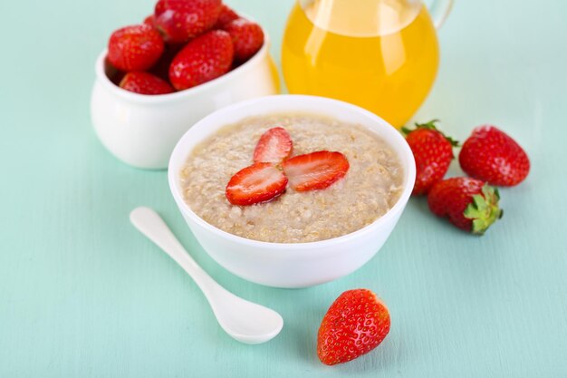 Tasty oatmeal with strawberry and juice on table closeup