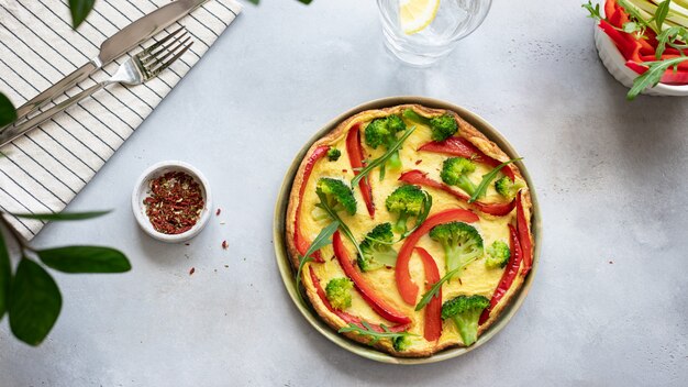 Tasty omelette with broccoli and sweet pepper on a grey concrete