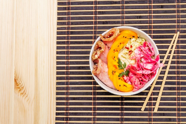 Tasty oriental noodles bowl. Pork, fermented cabbage, tomatoes, hot peppers, sesame seeds