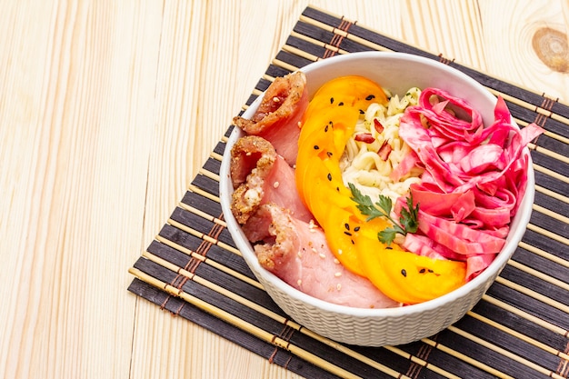 Tasty oriental noodles bowl. Pork, fermented cabbage, tomatoes, hot peppers, sesame seeds