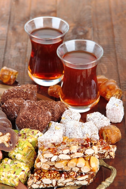 Tasty oriental sweets on tray and glasses of tea on grey wooden background