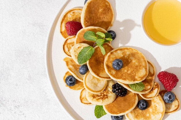 Tasty pancakes and berries on white plate.