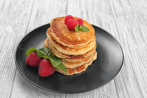 Tasty pancakes with berries and mint on plate