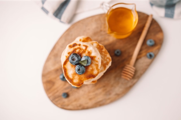 Tasty pancakes with fresh blueberries and syrup on a gray table on a light background top view flat ...