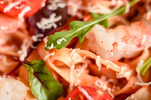 Tasty pasta with shrimp and tomato on a frying pan