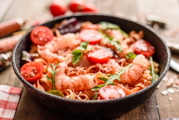 Tasty pasta with shrimp and tomato on a frying pan