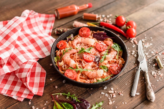 Tasty pasta with shrimp and tomato on a frying pan