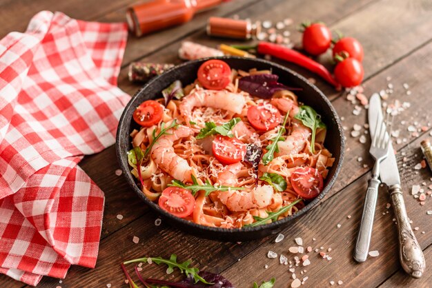 Tasty pasta with shrimp and tomato on a frying pan