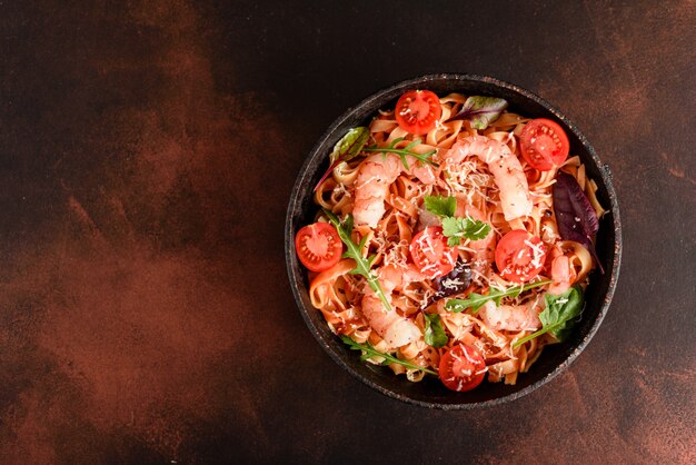 Tasty pasta with shrimp and tomato on a frying pan