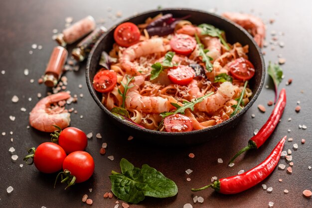 Tasty pasta with shrimp and tomato on a frying pan