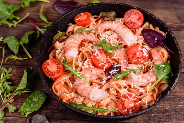 Tasty pasta with shrimp and tomato on a frying pan