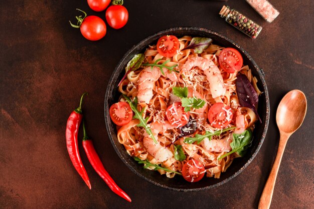 Tasty pasta with shrimp and tomato on a frying pan