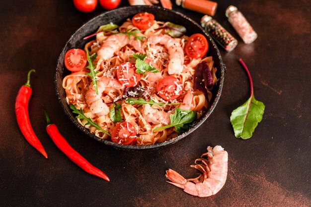 Tasty pasta with shrimp and tomato on a frying pan